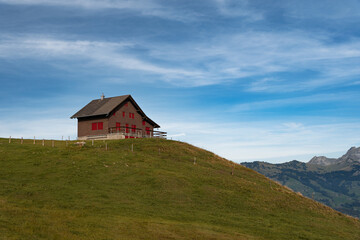 Red mountain hut in Swiss Alps, Switzerland against blue sky