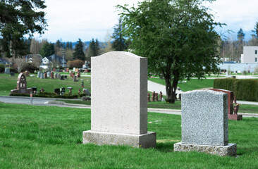 Two blank tombstones on green lawn.