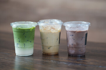 Close up glass of ice matcha green tea, iced latte and ice chocolate on wooden table of a coffee shop summer terrace, menu photography.