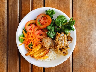  styrofoam lunch box with roast pork, salad, rice and potatoes on  wooden background