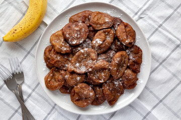 Homemade Banana Fritters with Powdered Sugar on a Plate, top view. Flat lay, overhead, from above.