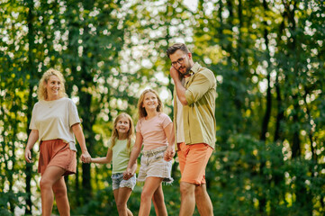 A young loving family is holding hands and strolling in nature.