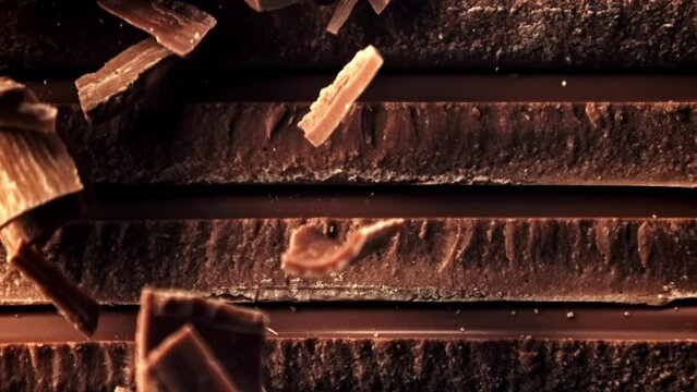 Super slow motion fall of grated, milk chocolate on a pyramid of chocolate slices. High quality FullHD footage