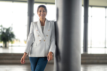 Pretty smiling business woman standing near the pillar