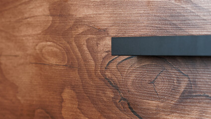 Black handle on a wooden drawer with decorative texture taxony - taxonium. Interior element. Photo....