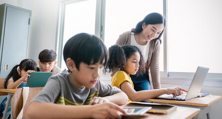 Pupil girl, teacher learn computer in classroom at elementary school. Student boy studying primary school. Children coding online in classroom. Education knowledge, successful teamwork concept banner