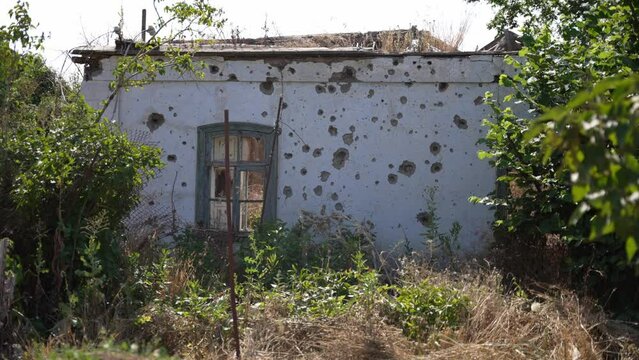 Facade of house with numerous holes from shrapnel, abandoned appearance. Concept of explosion, destruction, neglect