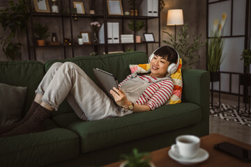 Fototapeta premium Woman sit at home use digital tablet to watch movie or have video call