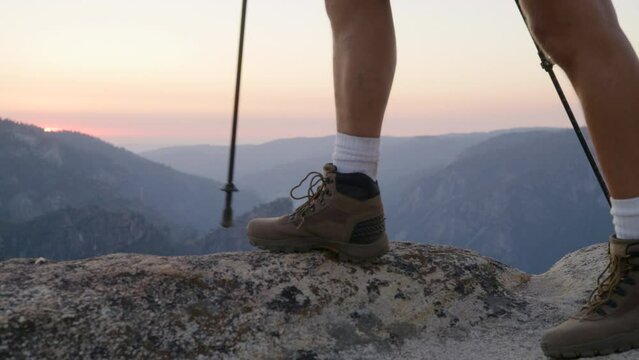 Legs of a hiker with hiking poles reaching the top of the mountain Half Dome in national park, incredible view of rocks with sunset in the background. High quality 4k footage