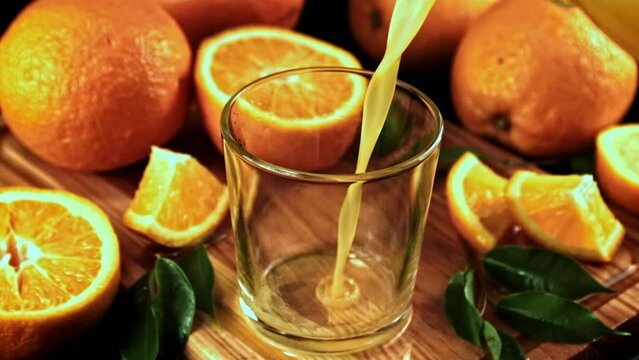 Orange juice with splashes is poured into the glass. High quality FullHD footage