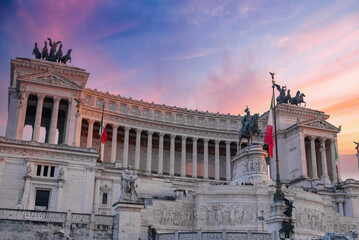 Obraz premium Neoclassical Altare della Patria monument in Rome, Italy. White marble structure with columns, sculptures, and Italian flags. Statue of Victor Emmanuel II on horseback on top.