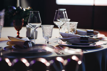 Beautifully organized event - round served table banquet ready for guests, round decorated table with empty plate, glasses, forks, napkin. Elegant dinner table 