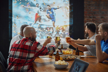 Emotional men, friends gathering together to watching online football match translation on TV, cheering up team, drinking beer. Concept of sport, championship, game, sport fans, leisure