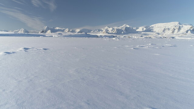 Infinitely, Infinitely polar snowy desert in Antarctica. South Pole frost surface. Scientific base. Snow covered mountains on horizon. Aerial view flight. Ice Landscape. Winter frozen ground drone fly