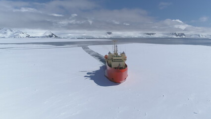 Icebreaker vessel navigating Antarctic waters - breaks through pack ice on its way. Aerial view. Featuring red color Laurence M. Gould Research Boat slicing through the Southern Ocean's ice expanse - obrazy, fototapety, plakaty