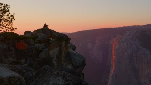 Fantastic view of majestic rock formations of famous Half Dome, lonely man admiring the beauty of impressive ancient rocks on the peak under orange skies. High quality 4k footage
