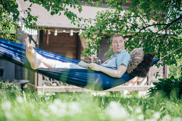 A man is resting and reading in a hammock. Day off and relaxation