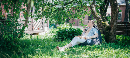 A man is resting and reading on a ottoman in the garden