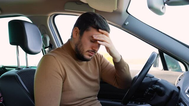 guy driver with his eyes closed sits in his car and rests. Drivers are often tired and work hard
