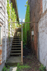 narrow wooden staircase between the walls of houses,