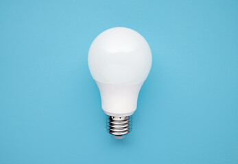 LED energy saving white bulb on blue background, top view