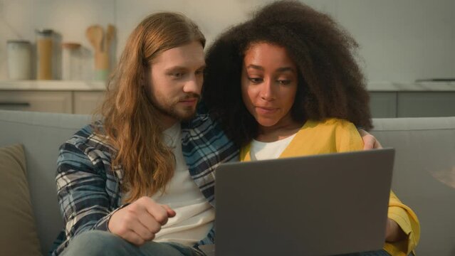 Multiracial couple diversity Caucasian man married African American woman together shopping at home couch insurance credit laptop buy goods discuss e-services purchase planning vacation e-commerce app