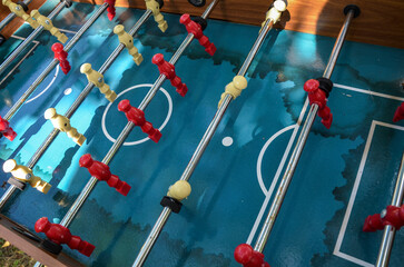 Close-up of well used foosball table, red and yellow players on worn surface. Ideal for illustrating recreational activities, game nights, or sports-themed content.
