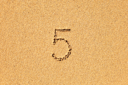 Number five 5 inscription written in the sand 