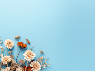 Dried flowers rest elegantly on a light blue backdrop, offering room for text in a flat lay