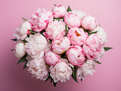 Pink and white peonies adorn a pink tabletop in a top-down view for web banners