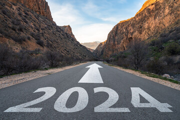 Asphalt road surrounded by mountains, 2024 written on the road, new year motivational concept