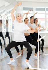 Group of dancers standing in grand plie ballet position in bright fitness room