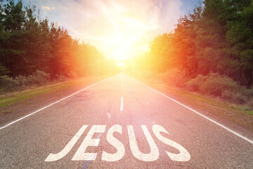 Asphalt road surrounded by mountains, Jesus written on the road. Christian concept. Jesus is the way