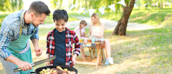 Little boy with father cooking tasty food on barbecue grill outdoors - obrazy, fototapety, plakaty