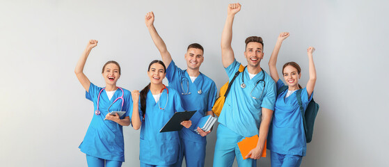 Group of happy medical students on light background - obrazy, fototapety, plakaty