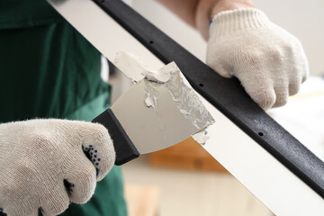 Male decorator with putty knives working in room, closeup