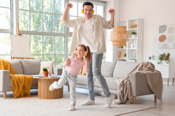 Cute little girl with her dad in headphones dancing at home