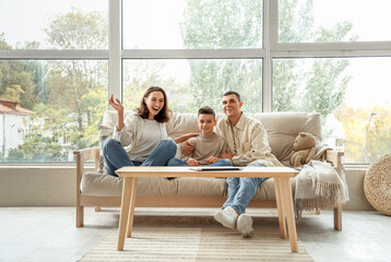 Little boy with his parents sitting on couch at home