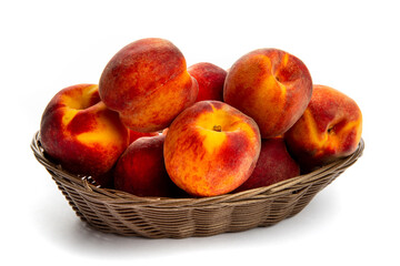 A woven basket of fresh, ripe peaches isolated on white