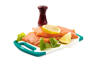 Pieces of skinless and boneless Atlantic Salmon filet on a white cutting board with garnish ready...