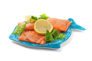 Salmon filet on a blue fish shaped plate with lemon slice and garnish ready to be cooked isolated on white