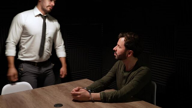 Dimly lit interrogation room with detecting removing handcuffs from a suspect and letting him go