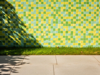 Natural grass casting harsh shadows on colorful mosaic tiles