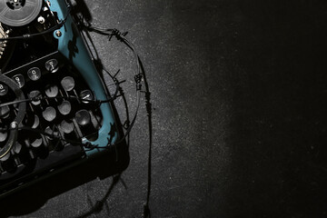 Vintage typewriter with barbed wire on black background. Printing ban concept