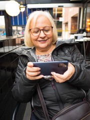 very happy blonde gamer grandmother playing on smartphone - 780151982