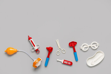 Toy first aid kit with glasses and scissors on grey background. Top view
