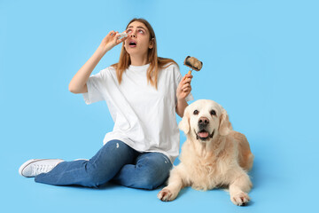 Young woman suffering from pet allergy with labrador dog on blue background