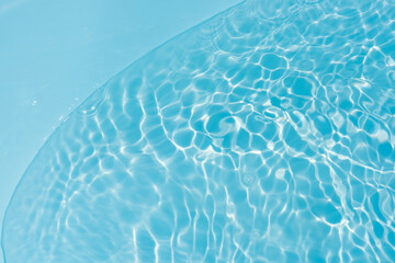 Bluewater waves on the surface ripples blurred. Defocus blurred transparent blue colored clear calm water surface texture with splash and bubbles. Water waves with shining pattern texture background.