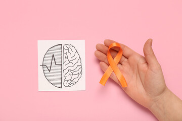 Drawing of brains and female hand with orange ribbon on pink background. Multiple Sclerosis...