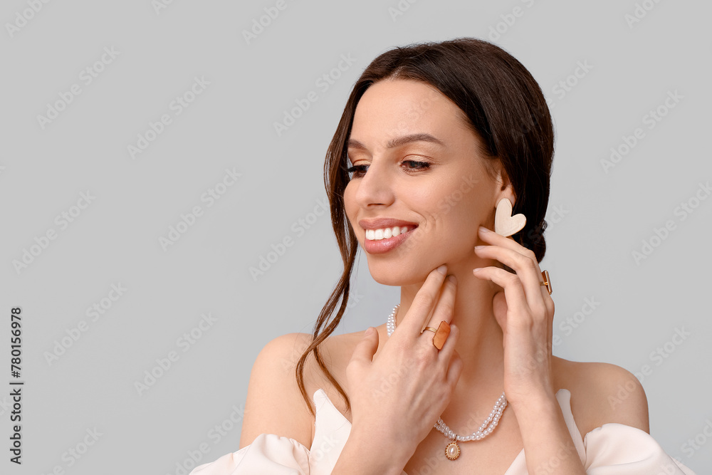 Wall mural Smiling young woman with elegant jewelry on grey background